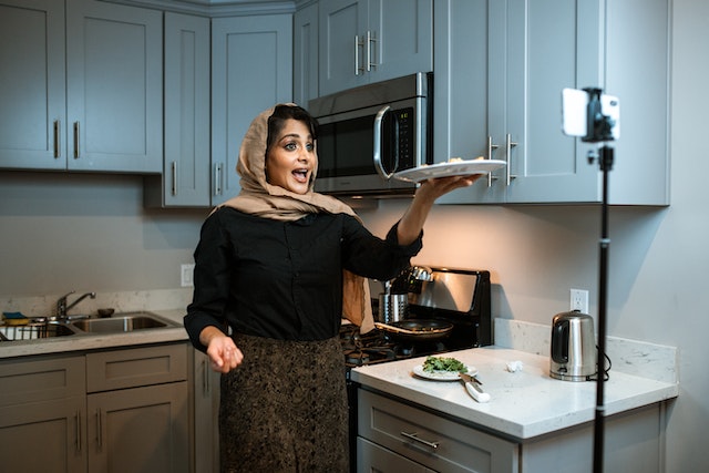 A woman influencer recording a video of the food she is cooking.