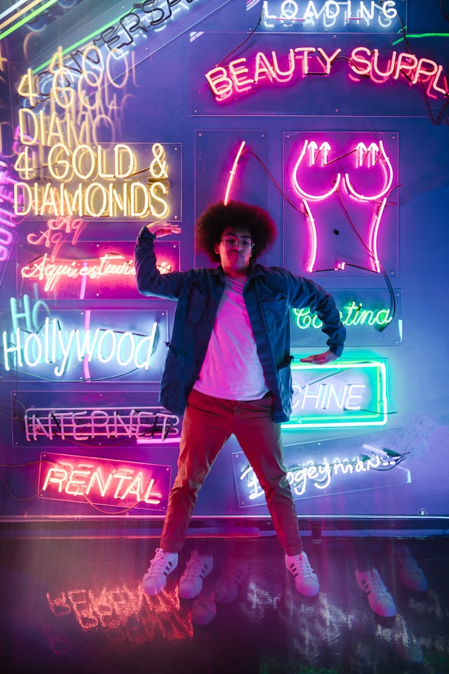 Een muzikant staat voor neonlichten en poseert.