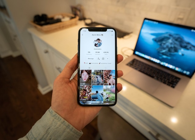 O imagine a unui telefon în mâna cuiva care arată pagina de profil a unui utilizator TikTok cu pictograma cu trei puncte în colțul din dreapta sus.