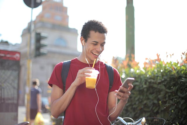 お酒を飲みながらスマホでビデオを見る人。 