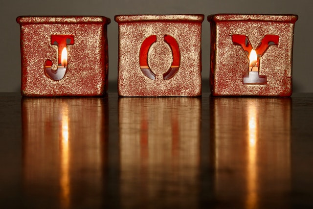 Three Christmas candle holders spell the word “JOY.”
