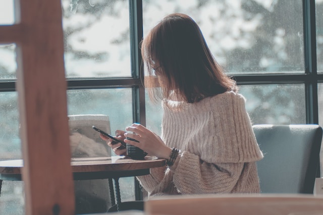 A TikTok influencer sitting and downloading TikTok videos on her phone.