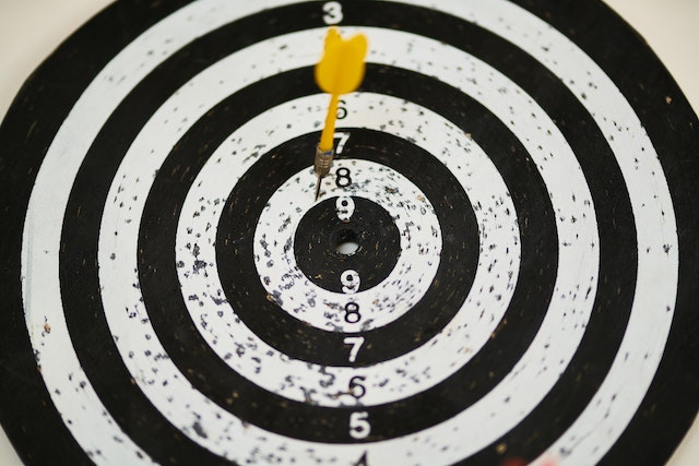 A yellow dart hits a dart board. 