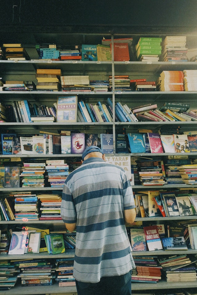 A man standing in front of a bookcase. 