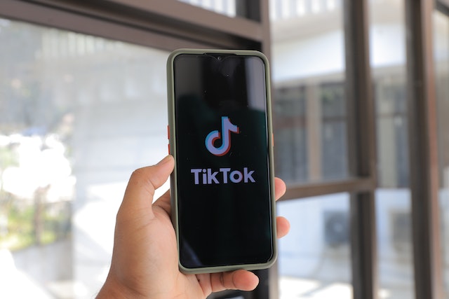A phone screen displays the TikTok name and logo as the app loads. 