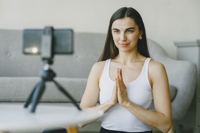 A girl doing yoga and recording a TikTok of herself. 