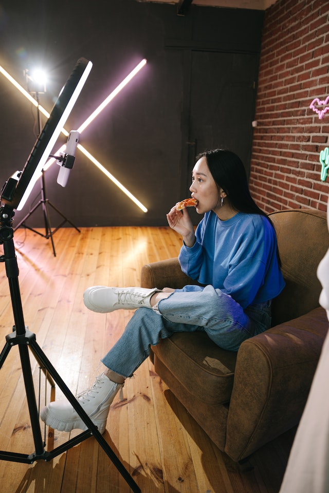 A girl sitting and eating while recording a video on TikTok.