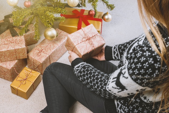 A woman places a Christmas gift under the tree. 