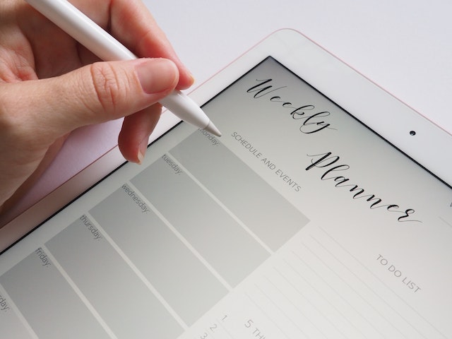 Una persona prende appunti sulla sua agenda settimanale digitale. 