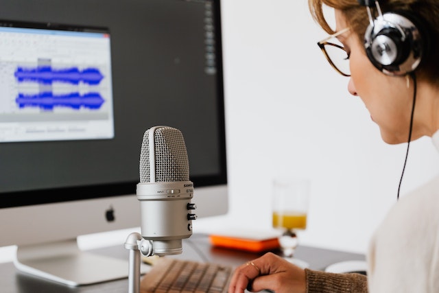 A woman speaks into a microphone while recording her voice.