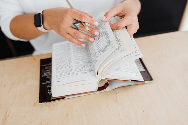 A person looks through a book to translate text. 