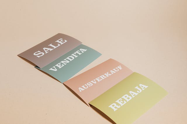 As placas exibem a palavra "SALE" (venda) em quatro idiomas diferentes. 