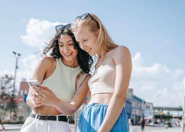 A lady showing her friend how to switch TikTok accounts on her phone without logging out.