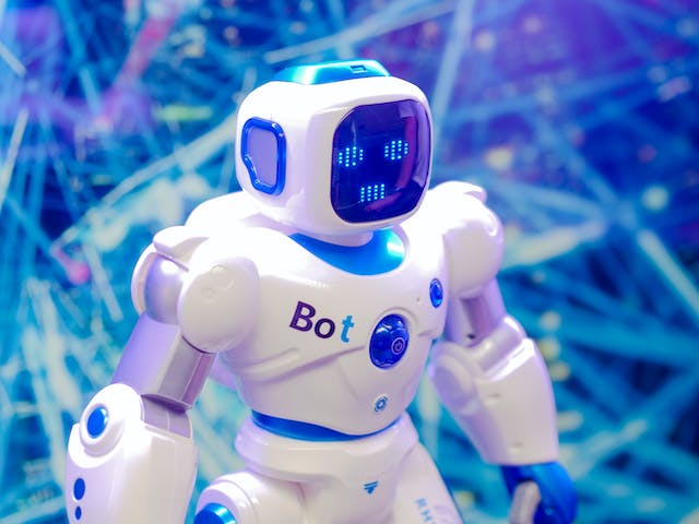 A photo of a blue and white bot in front of string lights. 
