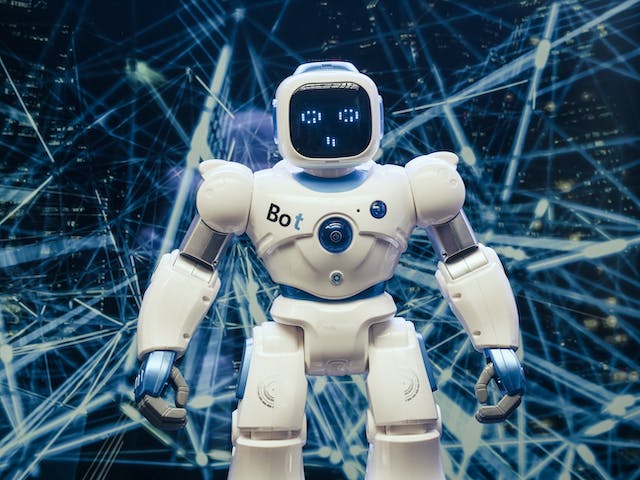 A photo of a small, white robot in front of intersecting blue lines.  