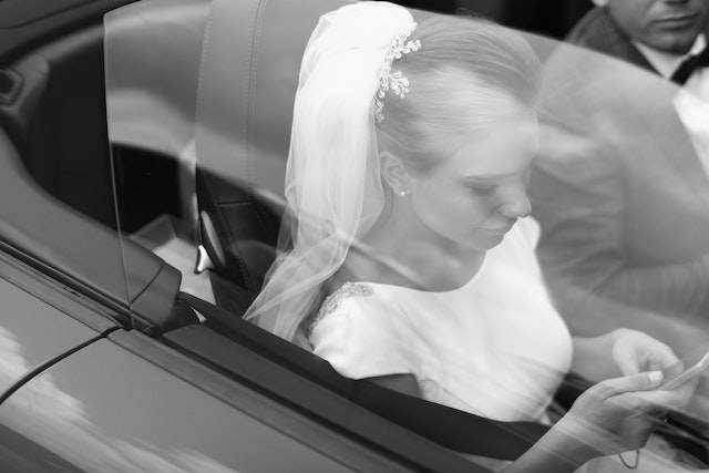 TikTokのフィードを見ながら車に座る花嫁。 