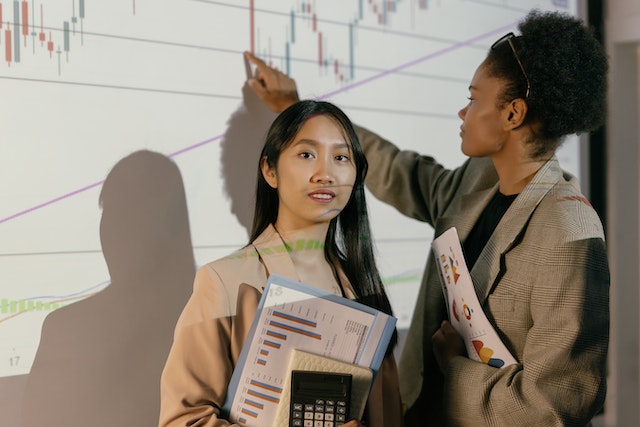 Two women present analytics data at a meeting. 