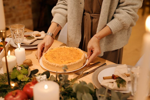 A person sets down a pie on the table for dessert. 