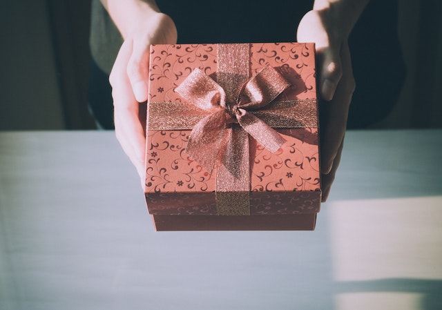 A person holds a brown gift box. 