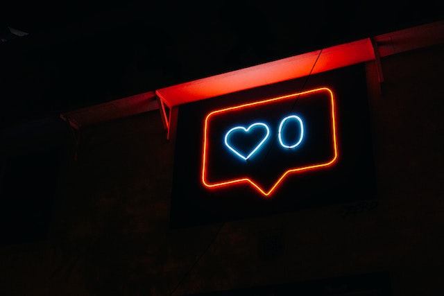 A black and red neon sign shows a heart and a zero, signaling zero likes.