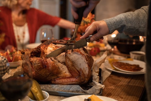 A person slices a roast turkey. 
