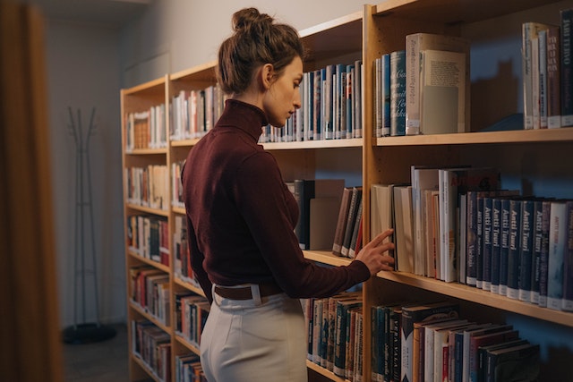 A girl searching for her next story from the bookshelf. 