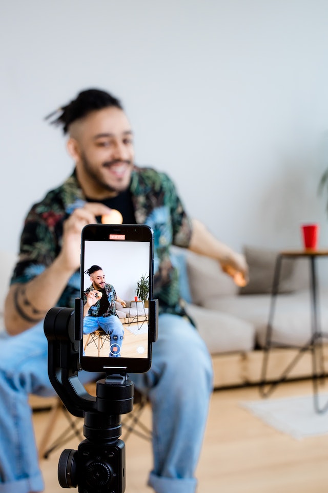 A man sitting and recording a video for TikTok. 