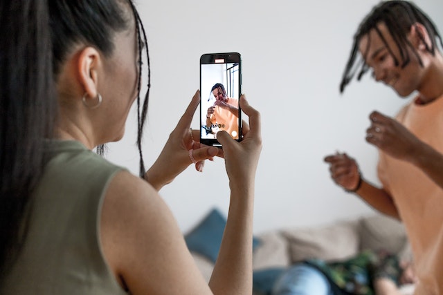 Uma mulher filma um homem enquanto ele dança para um vídeo do TikTok. 