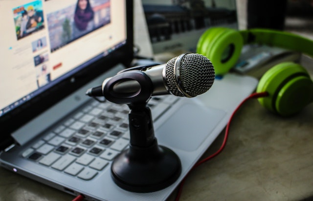 Um microfone em um pequeno suporte de microfone fica em cima de um laptop. 