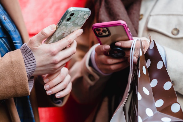 Uma foto em close-up das mãos das pessoas enquanto elas percorrem seus telefones. 