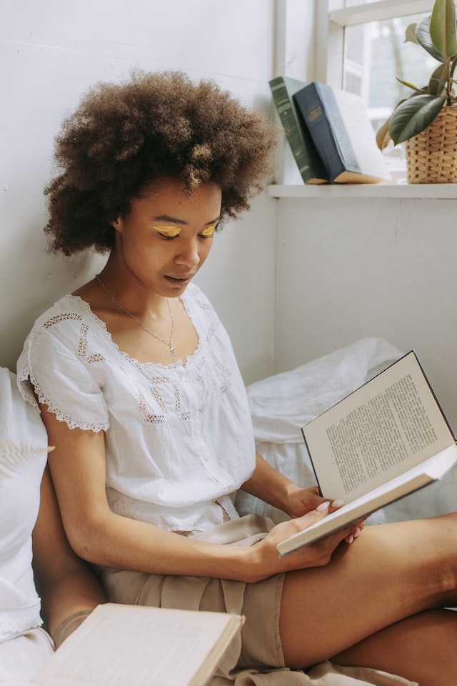 A girl sitting in her bed and reading.