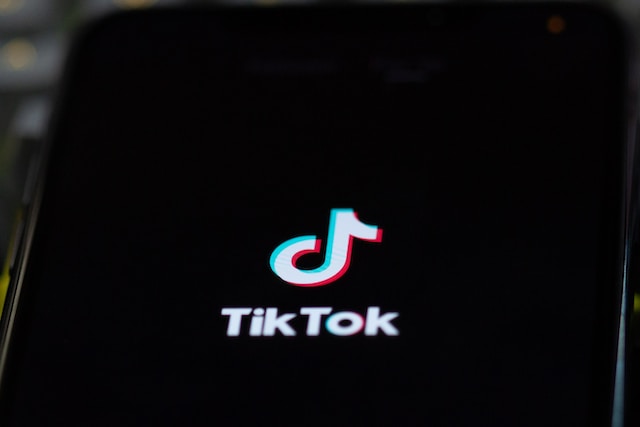 A photograph of a mobile phone screen displaying the TikTok logo on a black background.
