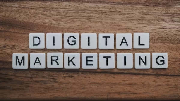 A picture of Scrabble tiles on a wooden board spelling out digital marketing.