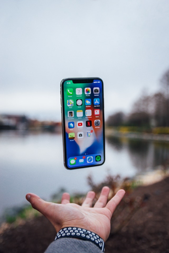 A person’s hand tossing an iPhone in the air.