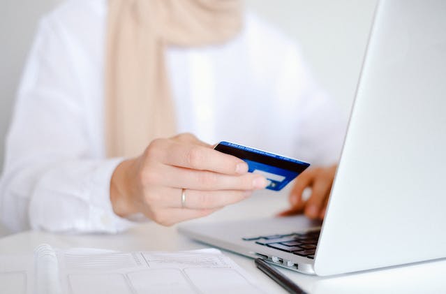 A person enters their credit card information on their laptop.