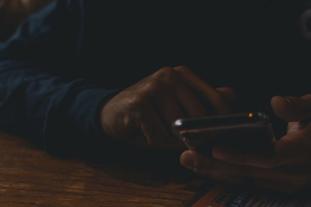 Een close-up van iemands hand die door zijn sociale media op zijn telefoon bladert.