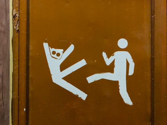 A door features a drawing of a human figure kicking another. 