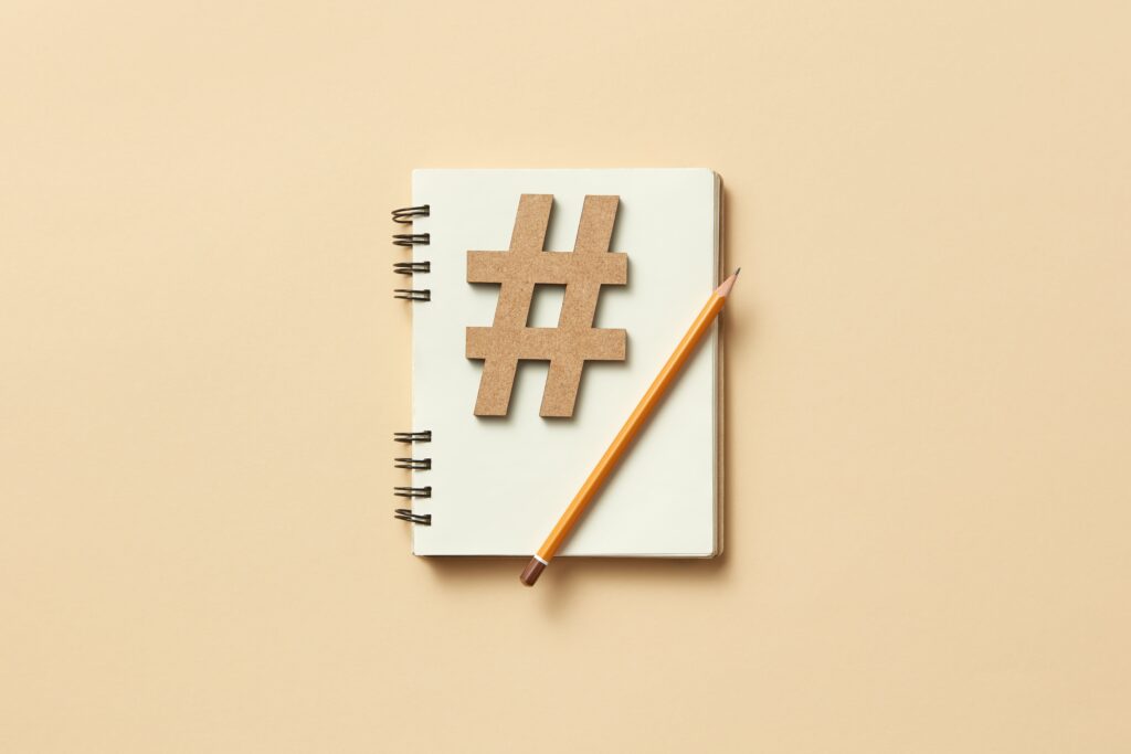 A cardboard cutout of a hashtag sign and a pencil lay on a blank page in a notebook.