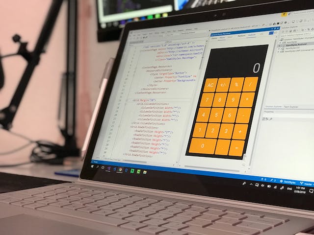 A laptop screen displays a calculator app. 
