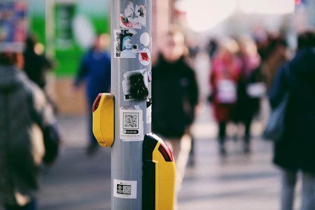 A metal pole with numerous QR code stickers on it. 