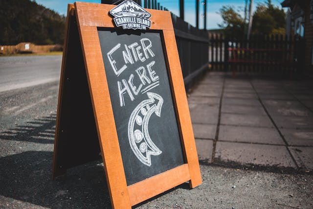 A chalkboard sign displays the words “ENTER HERE” and a curved arrow underneath.
