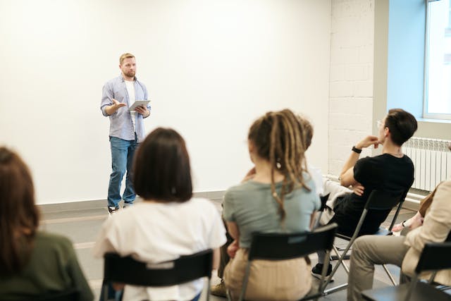 An image of a speaker standing in front of an engaged audience. 