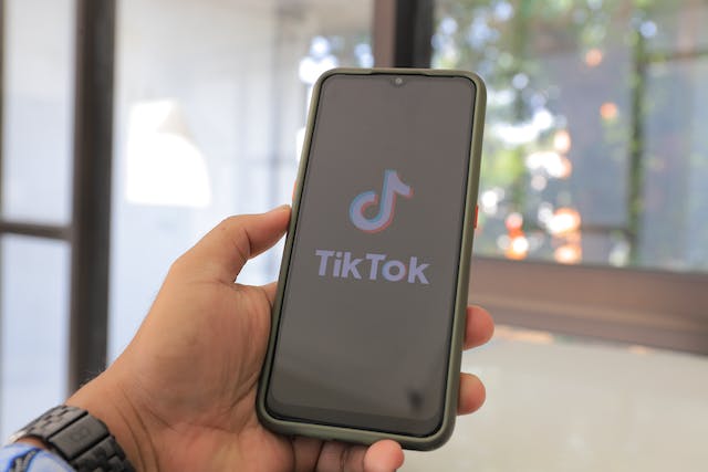A phone displays the TikTok logo and name. 
