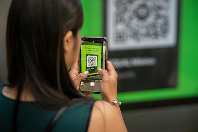 Uma mulher escaneia um código QR usando seu telefone. 