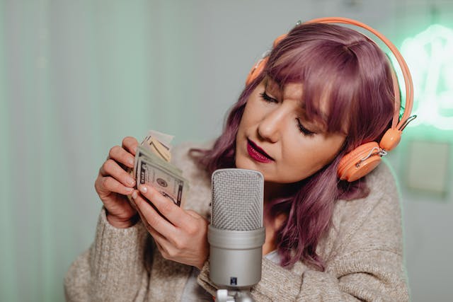 Uma mulher usando um fone de ouvido e falando em frente a um microfone conta seu dinheiro.
