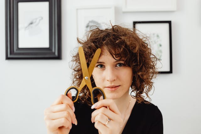 A woman holds up a pair of scissors. 