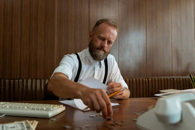 A man stacks coins on a table. 