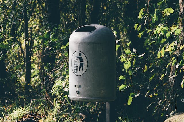 A photo of a gray metal trash bin. 