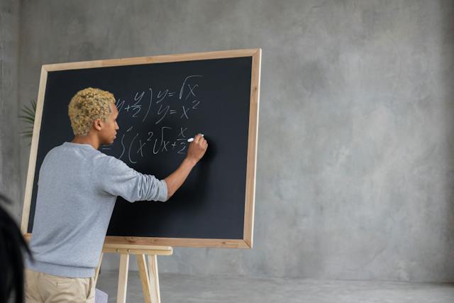 A person performs calculations on a chalkboard. 