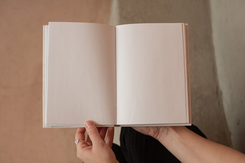O persoană ține în mână un caiet cu pagini albe. 